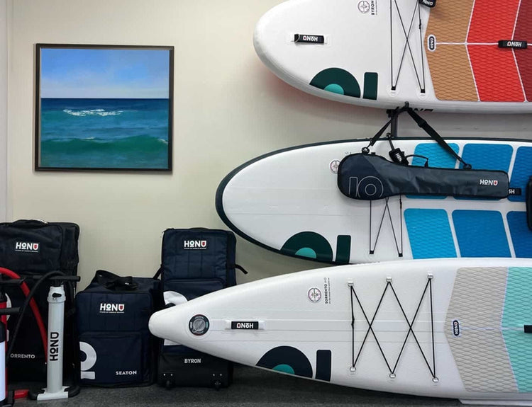 Honu inflatable paddleboards displayed with their pumps and bags.